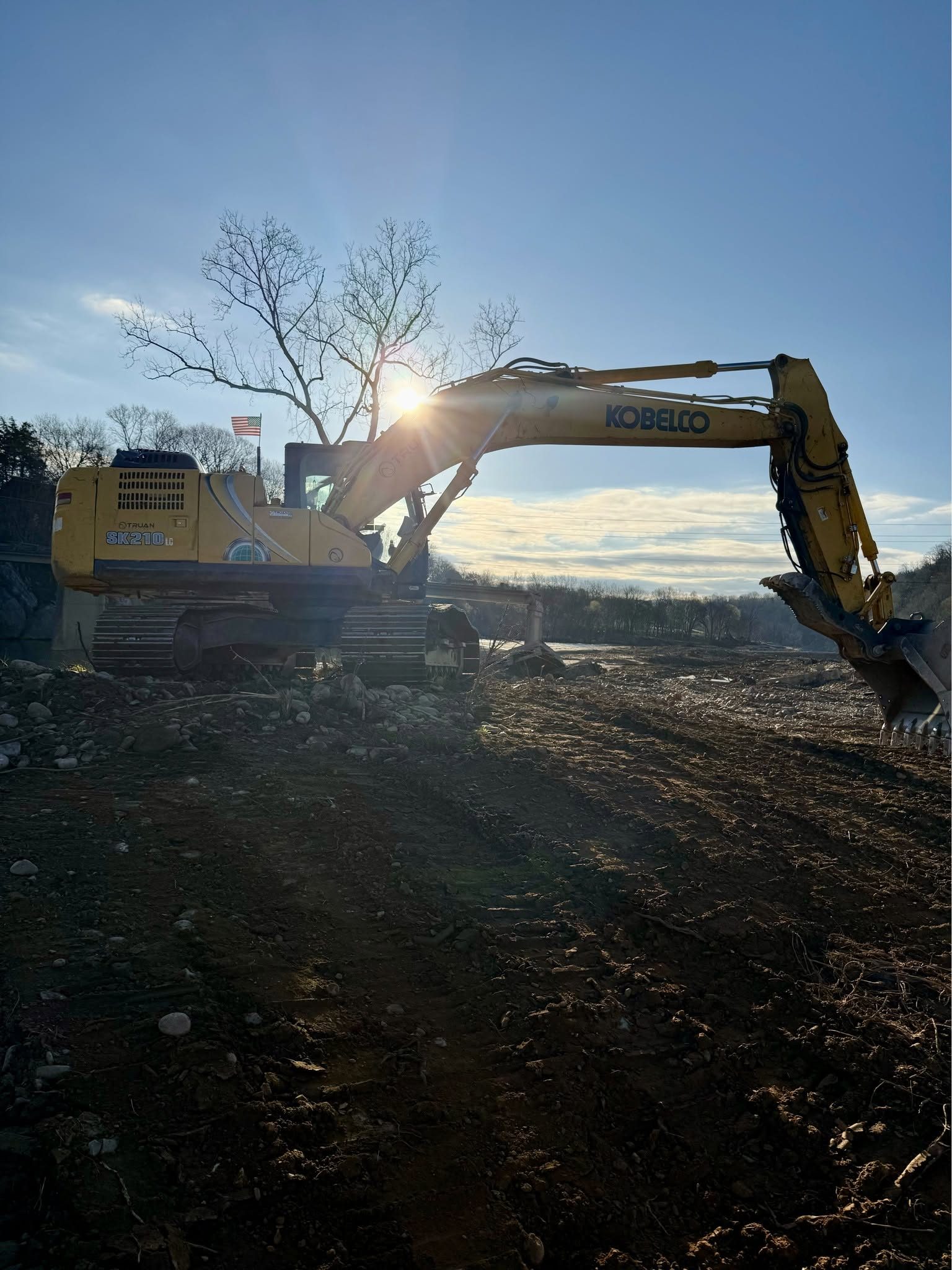 Viking Grading Solutions excavator working a creek-side site at golden hour in the western North Carolina mountains