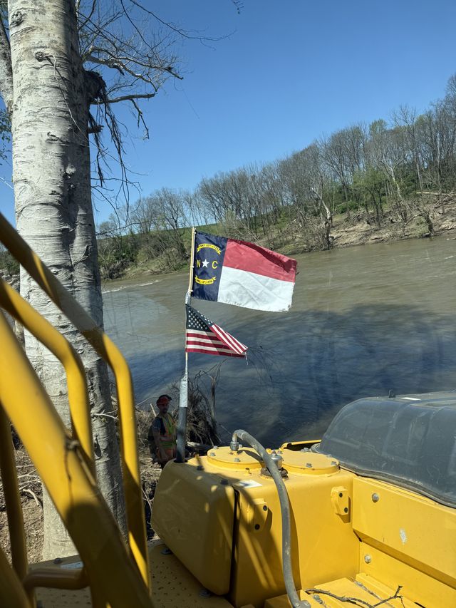 American and North Carolina flags flying from Viking Grading equipment on a river job. Veteran-owned and proud of it