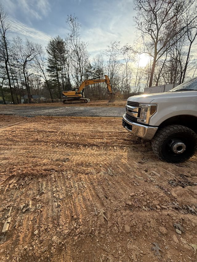 Work truck and excavator on a graded building pad at golden hour, western North Carolina grading job